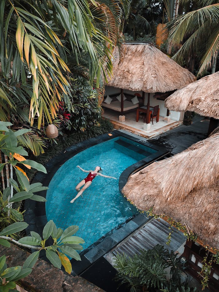 pexels-photo-3225531 A woman enjoying leisure time floating in a tropical resort pool surrounded by lush greenery.
